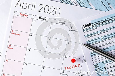 April 2020 calendar with the 15th pinned with tax day text, and 1040 tax forms on the sides Editorial Stock Photo