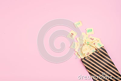 April Fools ' Day celebration background. Paper bag with many paper sheets with the words haha. 1 April mockup on pink background. Stock Photo