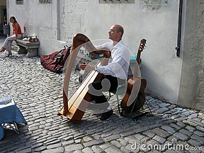 April 10, 2023, Rome, Italy: A street musician plays the harp in the city square and entertains people Editorial Stock Photo