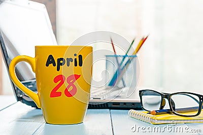 April 28th. Day 28 of month, calendar on morning coffee cup, business office background, workplace with laptop and Stock Photo