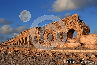 Aqueduct in Caesarea at sunset with moon Stock Photo
