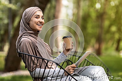 Arab girl with digital tablet drinking coffee at park Stock Photo