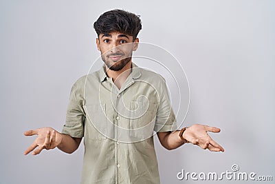 Arab man with beard standing over white background clueless and confused with open arms, no idea concept Stock Photo