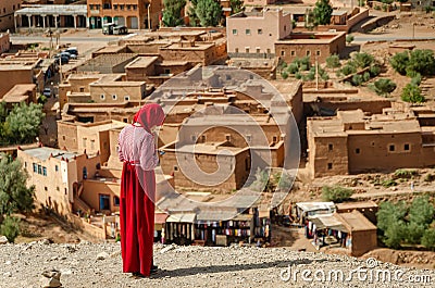 Arab woman dressed in red looks at the mobil in the Kasbah Ait Ben Haddou in Ouarzazate, Morocco October 2019 Editorial Stock Photo