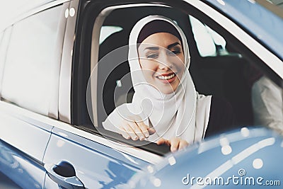 Arab woman sits in new car and looks out of window Stock Photo