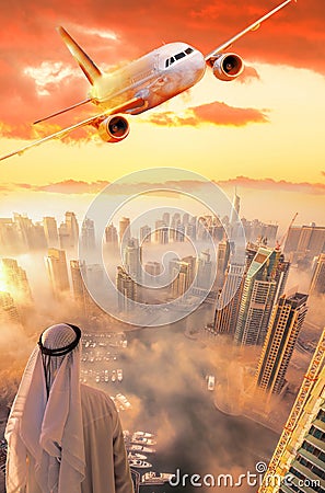 Arabian businessman watching Dubai Marina with Plane flying against colorful sunset in Dubai city, United Arab Emirates Stock Photo