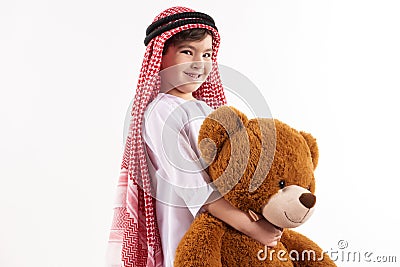 Arabian happy boy in keffiyeh hugs stuffed toy. Stock Photo