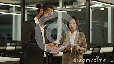 Arabian happy businessman with many money man count banknotes and sad Asian businesswoman woman with little finance Stock Photo