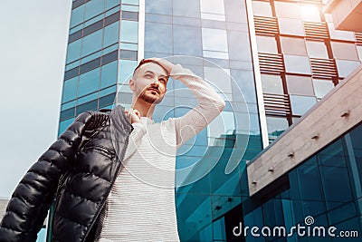 Arabian man holding his coat and walking in city center. Young man puts coat on shoulder. Stylish handsome hipster Stock Photo