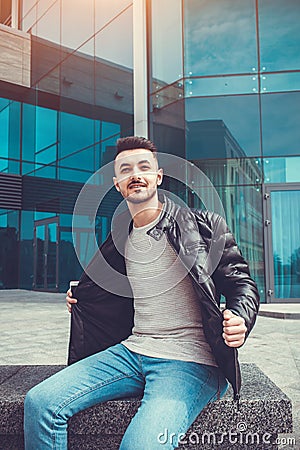 Arabian man taking his coat off in front of modern building. Young man shows off Stock Photo