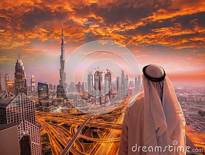 Arabian man watching cityscape of Dubai with modern futuristic architecture in United Arab Emirates. Stock Photo