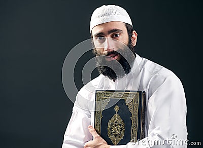 Arabian muslim man with beard holding the holy book Quran Stock Photo