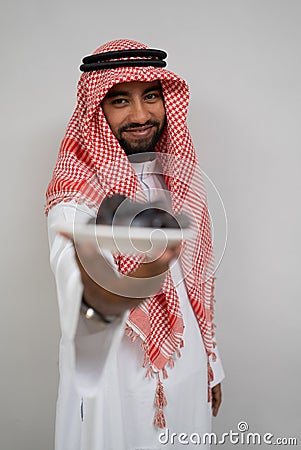 an arabian in a turban smiles while carrying and offering a plate of dates to the camera Stock Photo