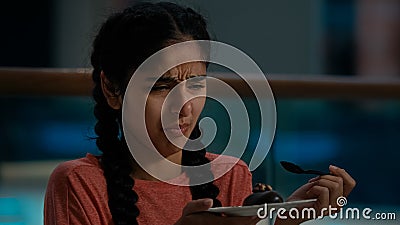 Arabian young woman client eat musty chocolate cake with teaspoon distasteful spoiled brownie in cafe bad unhealthy Stock Photo