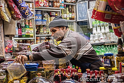 Arabic aged shopkeeper from Iran arranging food items in his shop at souk mubarakiya, Kuwait City Editorial Stock Photo