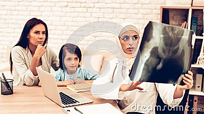 Arabic Doctor Appointment Holding X-Ray Film. Pediatrician Appointment Mom with Sick Son. Confident Muslim Female Doctor Wearing Stock Photo