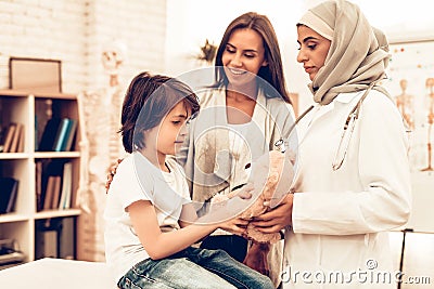 Arabic Doctor Giving Toy to Little Cute Patient. Confident Muslim Female Doctor. Child at the Pediatrician. Hospital Concept. Stock Photo