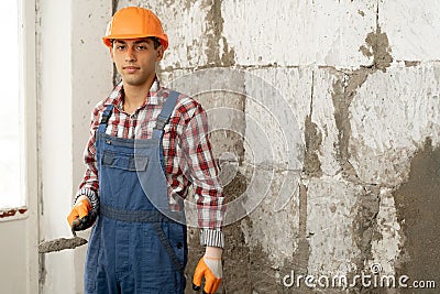 Arabic man master plasters the walls, portrait of builder in hard hat making repairs in the apartment, repairing and Stock Photo