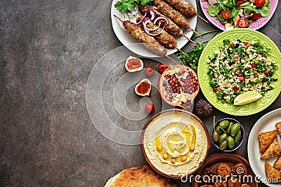 Arabic and Middle Eastern dinner table. Hummus, tabbouleh salad, Fattoush salad, pita, meat kebab, falafel, baklava, pomegranate. Stock Photo