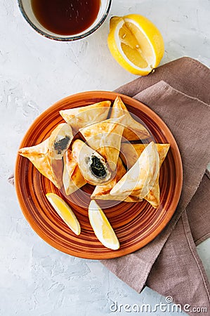 Arabic and middle eastern food concept. Fatayer sabanekh - traditional arabic spinach triangle hand pies dates and tea on a white Stock Photo