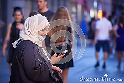 Arabic Middle eastern young woman wearing islamic scarf veil wearing a face mask under the chin, during covid 19 coronavirus Editorial Stock Photo