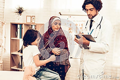 Arabic Pediatrician Appointment Mom with Sick Son. Confident Muslim Male Doctor. Hospital Concept. Healthy Concept. Pediatrician Stock Photo