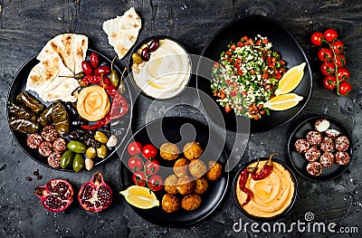 Arabic traditional cuisine. Middle Eastern meze platter with pita, olives, hummus, stuffed dolma, labneh cheese balls, falafel. Stock Photo