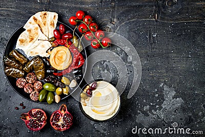 Arabic traditional cuisine. Middle Eastern meze platter with pita, olives, hummus, stuffed dolma, labneh cheese balls in spices. Stock Photo