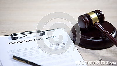 Arbitration agreement document on table, gavel lying on sound block, dispute Stock Photo