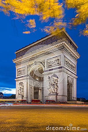 Arc de Triomphe at dusk in Paris in France with traffic of cars light trails and yellow leafs moved by the wind Stock Photo