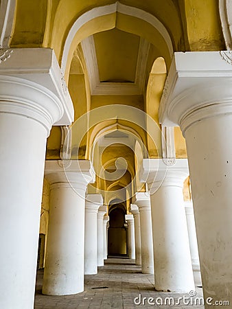 An arcaded corridor with tall, white columns and yellow arches at the ancient Tirumalai Editorial Stock Photo