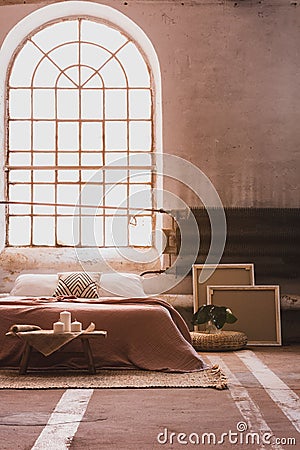 Arch window in a wabi sabi bedroom interior with a bed and iron radiator Stock Photo