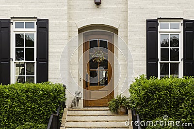 Arched front door with statue and shrubs Stock Photo