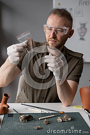 Archeology concept. Scientist archaeologist studying ancient artifact sitting in his office working overtime Stock Photo