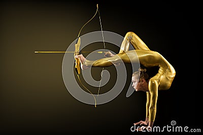 Archer Shooting by Legs with Gold Bow and Arrow. Flexible Gymnast aiming Target standing on Hand upside down. Goal Achievement Stock Photo