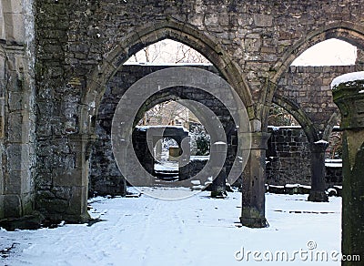 Arches and columns in the ruined medieval church in hebden bridge west yorkshire with snow covering the ground in winter Stock Photo