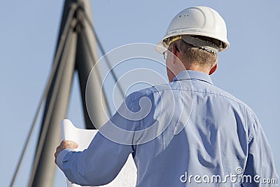 Architect or engineer reading a construction plan in front of industrial background Stock Photo