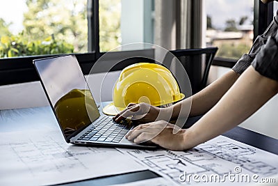 Architect engineers are using laptops to check house plans and print them out on paper after designing. Stock Photo