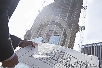 Architect holding blueprint of building at a construction site, midsection Stock Photo