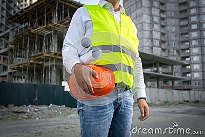 Architect in jacket posing with red helmet at construction site Stock Photo