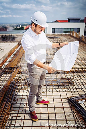 Architect looking at paper plans on construction site. Details of construction building and workers Stock Photo