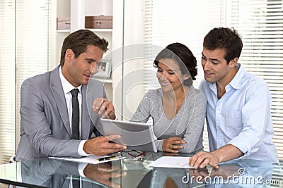 Architect presenting a new project to a smiling young couple Stock Photo