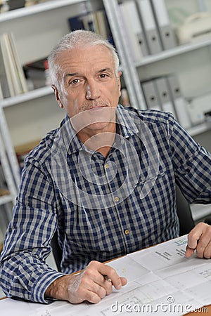 Architect sat at desk with blue prints Stock Photo