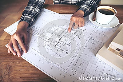 Architect working on an architecture model with shop drawing paper and coffee cup on table Stock Photo