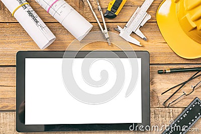 Architect workplace. Tablet with white blank screen, project construction blueprints and engineering tools on wooden desk, copy sp Stock Photo