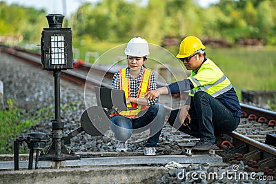 Architects and engineers point to railroad switches and use laptops to point out railway tracks that need to be accelerated in the Stock Photo
