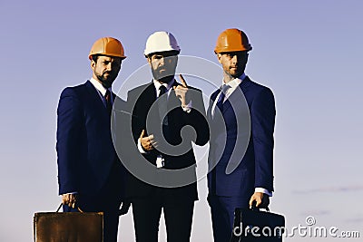 Architects hold clip folder and briefcases. Leaders with beard and concerned faces discuss project. Stock Photo