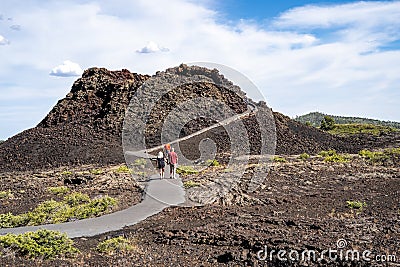 Arco, Idaho - June 30, 2019: Hikers walk up the Spatter Cones trail, a paved walkway leading to a cinder cone wi in Craters of the Editorial Stock Photo