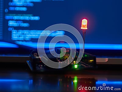 Arduino with Red Light-Emitting Diode against a Notebook Screen Stock Photo