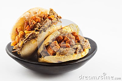 Arepas filled with shredded beef and pork rind served in a black ceramic dish Stock Photo